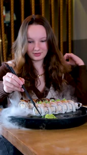 여자가 젓가락으로 조각을 어두운 초밥을 소녀가 유럽의 블라우스 증기가 뿌려진 — 비디오