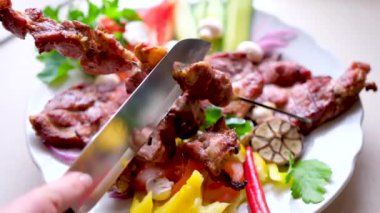 Açık havada mangal kömüründe şiş kebap. Adam pişirilmiş domuz barbeküsünü bıçakla şişten çıkartıyor. Yüksek kalite 4k görüntü
