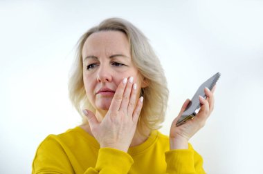 Duygusal olarak şok olmuş genç bir mankenin akıllı telefonuyla ekrandaki cihaza dikkatle bakması ağzını eliyle kapatması, haberlere şaşırması. İnsanlar ve duygular