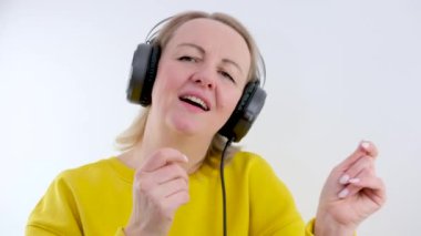 Gülümseyen çekici kadın kulaklıkla müzik dinliyor sarı arka plan