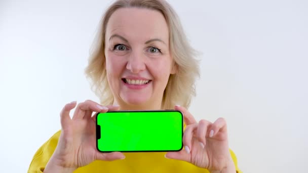 Улыбающаяся Женщина Смотрит Камеру Указывает Зеленый Экран Веб Шаблон Смартфоне — стоковое видео
