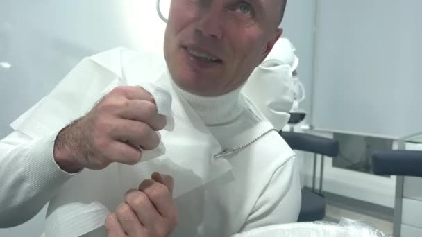 医者と話すナプキンで顔を拭いて歯医者と話す白い背景のシャツ大人のための医療歯科治療義肢のナプキン無菌衛生 — ストック動画