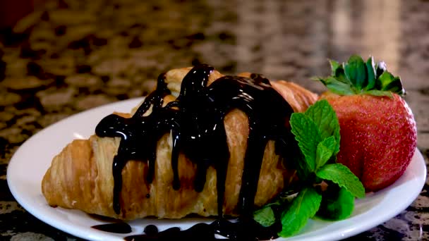 草莓巧克力羊角面包站在大理石桌上的白盘上 一滴滴的巧克力加薄荷新鲜草莓在盘子里的早餐糕点上 法国烹饪餐馆 — 图库视频影像