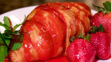 Çilek reçeli kruvasana dökülür. Bir sürü reçel taze hamur işlerinin üzerine akar. Gözenekli bir yapı.