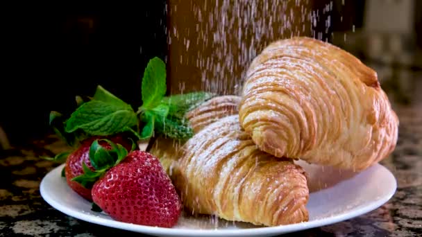 ゆっくりと粉砂糖はイチゴとミントとプレート上に2つの新鮮なクロワッサンを振りかけるそれは雪のおいしい非現実的な美しい緑白赤フランスの朝食料理レストラン料理を提供しています — ストック動画