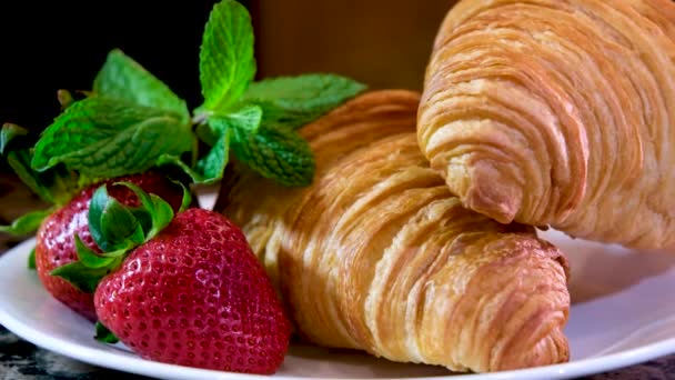 在白色盘子里放着美丽别致的视频两个牛角面包巨大的草莓和薄荷叶相机慢慢地把拍摄美味的法国早餐餐厅的镜头拉开 提供新鲜的 不真实的 美丽的 别致的糕点 — 图库视频影像