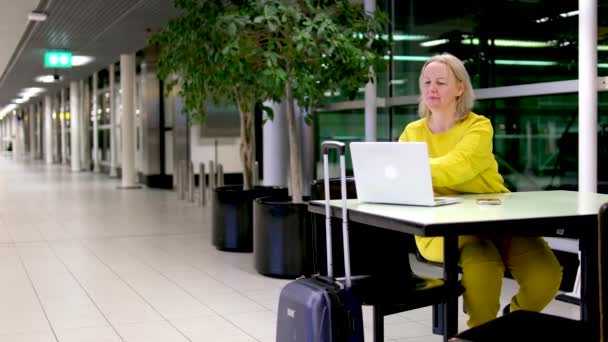 空港ターミナル 笑顔の女性はフライトを待ち ラップトップを使用し インターネットを閲覧し 電子ビジネス オンラインショッピングを行います 航空会社の搭乗ラウンジでコンピュータ上で女性のリモートワークを旅行 — ストック動画