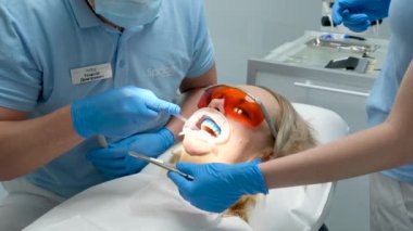 Erkek doktor kadın hastayı kabinesinde tedavi ediyor. Diş muayenehanesinde ağzı genişletilmiş genç bir kadının yakın çekimi. Diş Aracı, Süpürge, Matkap, Ekipman, Klinikteki Enstrümanlar