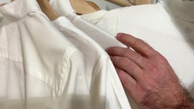 Müşterinin ellerine yakın çekim. Tanınmayan bir adam, giyim mağazasından bir gömlek seçiyor. Yüksek kalite 4k görüntü