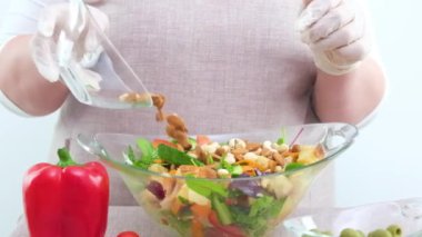 Şefin mevsimi ve çam fıstığı serpintileri şeffaf bir tabakta sebze, ot ve fındık salatası. Kadınlar çam fıstığı salatası serperler. Yavaş çekimde yakın çekim, renkli. Yüksek kalite