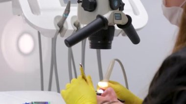 Tedavi hastaları için mikroskop aletleri olan modern diş kliniği. Doktor koruyucu eldiven takıp tıbbi mikroskop takıyor. Erkek dişçi mikroskop kullanır. Tıbbi ekipman, dişçi kliniği Yüksek kalite