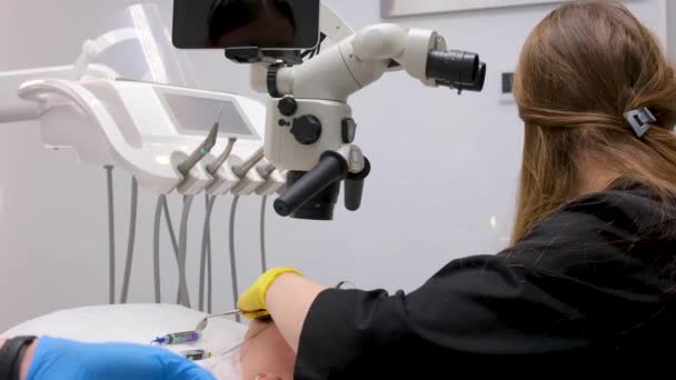 Zahnärztin Mit Maske Und Handschuhen Unter Verwendung Eines Endodontischen Binokularmikroskops — Stockvideo