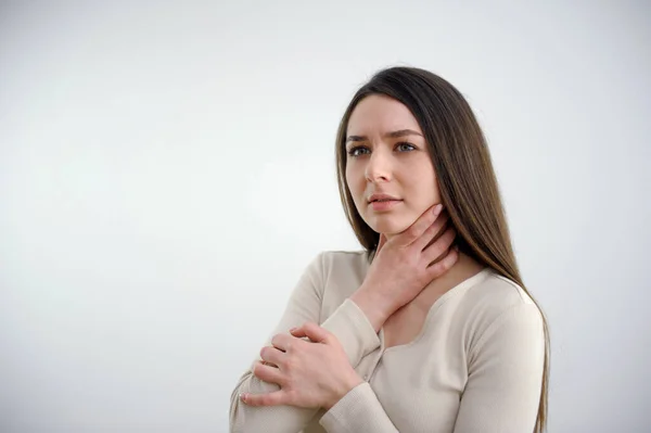 Sore throat. Closeup of beautiful young woman hand touching her ill neck. She suffering from throat pain, painful swallowing. High quality photo