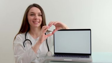 Hintli kadın doktor dizüstü bilgisayar kullanarak beyaz önlük giyer. Çalışma masasında oturup beyaz ekran taraması yapar. Sağlık hizmetleri tıbbi sağlık web sitesi teknik konsepti. Omuz görünümünü kapat