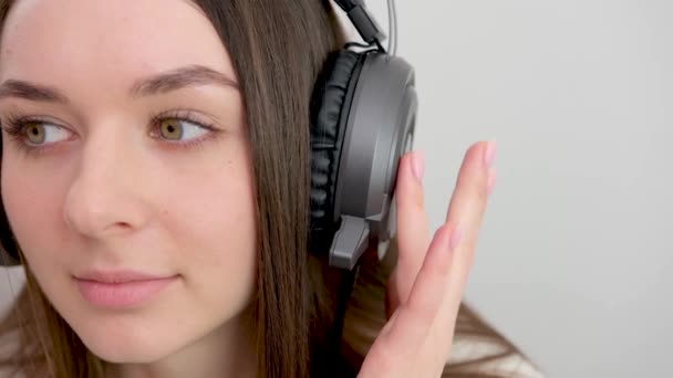 ヘッドフォンイヤフォンでポッドキャスト電子書籍音楽の歌歌手ロックバンドを聞いて笑顔の原因アジアの若い女性 白い背景に隔離された携帯電話上のサウンドトラックを選択 — ストック動画