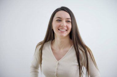 Güzel, neşeli, sarışın bir kadın, sıradan giyinmiş, kameradan memnun bir şekilde stüdyo duvarında izole edilmiş güzel bir kadının mutlu bir fotoğrafını çekiyor.