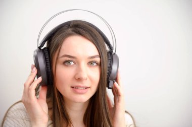 Panoramic Side Ptofile 'da, şık giyinen, arka plan duvarına izole edilmiş, beyaz kablosuz kulaklıklar takan, müzik dinleyen ve...