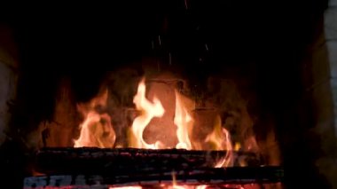 Oturma odasındaki şöminenin içinde yanan odunları kapatın. Bir evin oturma odasındaki şöminede yanan odunları yakın plan yapın. Sıcak ışık ve sıcak Noel atmosferi