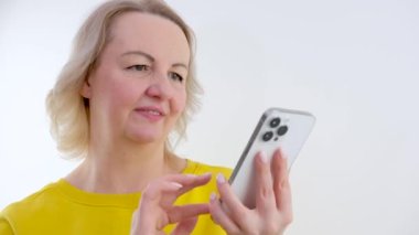 Akıllı telefon tutan beyaz kadın göz yorgunluğu çekiyor, esmer kız kuru gözlerde ağrıdan muzdarip, kötü görme sorunu, mavi arka plan stüdyosunda izole edilmiş. Yüksek kalite