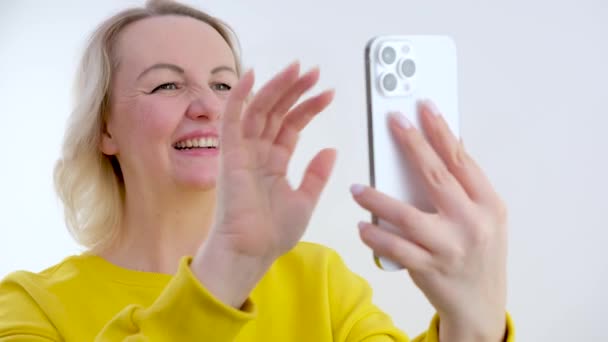 マイク手を振ってワイヤレスヘッドフォンで優しい笑顔千年のビジネスマンの女性は 同僚とのオンライン会議Webカメラビデオ通話会話を開始ハロージェスチャーを作ります — ストック動画