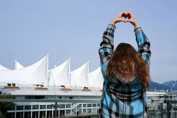 Canada Place, Vancouver, British Columbia, Canada Radiance of the Seas Cruise Ship Docked at Canada Place. girl teenager woman stands with her back to the camera makes heart travel with her hands