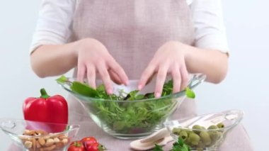 Yakın plan kadın elleri taze lezzetli salatada ahşap kaşıkla karıştırılmış sebzeler, tanınmayan anne ve kız vejetaryenler kırmızı biber yeşiliyle yemek tabağı hazırlıyorlar.