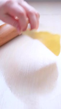 Çaba sarf eden kadın elleri ahşap bir oklava üzerinde, masaya ince bir hamuru yuvarlıyor. Hamur tatlısı için az para. Yakın plan. Yüksek kaliteli FullHD görüntüler