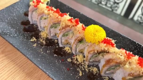 黄色の花で飾られた黒い皿にカニとエビの寿司寿司ロール 寿司融合 真木融合は日本料理です 新鮮でおいしい寿司 カニの棒揚げ アボカド アスパラガス — ストック動画