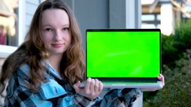 Dizüstü bilgisayarı olan güzel genç kız yeşil ekran krom anahtar reklamı. Verandada oturuyor. Mavi ceketli.