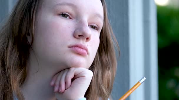 悲しいです集中顔の若いです十代の女の子保持A鉛筆で彼女の手考えそれに置くために彼女の口の場所のためにテキストトレーニング学校のレッスン思春期の子供の問題 — ストック動画