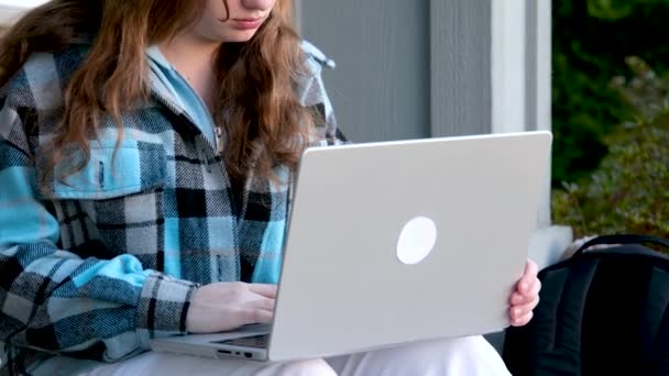 图片中 一个年轻美丽的快乐的女人在户外与笔记本电脑一起工作时 在门廊上美丽的少女微笑 — 图库视频影像