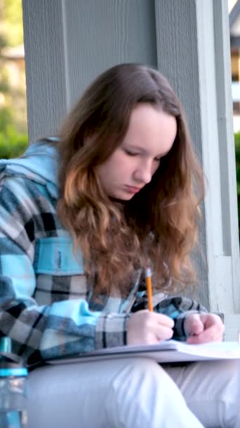 若い十代の少女の美しい顔を閉じる少女は引いたり書き込みにもたれかかったり緑の葉の教室の建物の背景を背景に見下ろし夢を見て期待悲しみ — ストック動画
