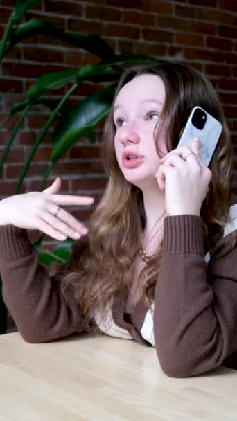 Nastolatka Dziewczyna Kawiarni Rozmawia Przez Telefon Ekspresyjnie Macha Ramionami Opowiadając — Wideo stockowe