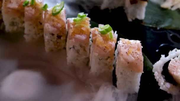 乾燥した氷の蒸気の黒い石板のカリフォルニア寿司は 箸で1つの寿司をウナギとマグロで置きます伝統的な寿司巻きセット 日本の魚介類 高品質4K映像 — ストック動画