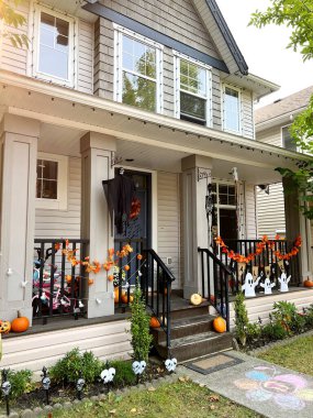 Evdeki cadılar bayramı süsleri verandada asılı duruyor. Balkabağı İskeletleri, Kemikleri ve Asılmış Adamları tanıtıyorlar. Vancouver Özel Cadılar Bayramı Kutlamaları.