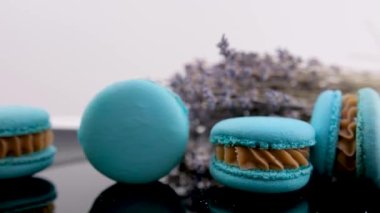 Piramidin arka planında daireler çizen mavi badem kurabiyesi ve beyaz arka plandaki diğer tatlılar. Kadın el yazmaları tatlı yapıyor. Masada lezzetli öğle yemeği kurabiyeleri pişirirken güzel bir video hazırlıyorlar.