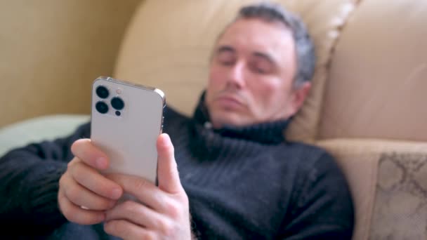 Чоловік Лежачи Ліжку Дивлячись Новий Телефон Iphone Про Макс Відмінний — стокове відео