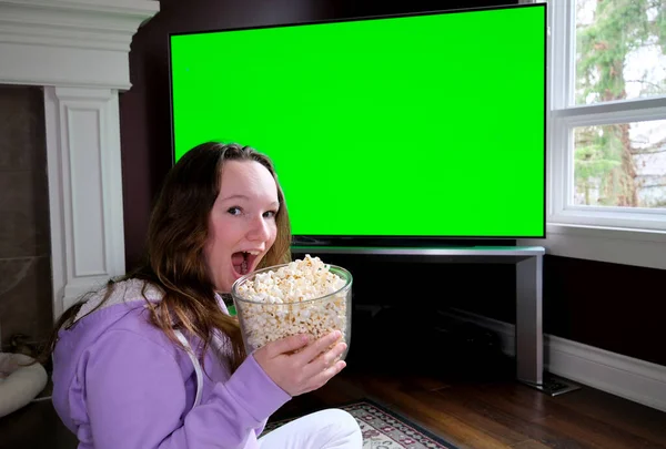 Woman Watching Green Chroma Key Screen TV Relaxing. Girl in Cozy Room Watching Sports Match, News, Sitcom TV Show or a Movie on Green Screen eating popcorn and Change TV channels