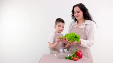 Anne ve oğlu salata hazırlıyor. Mutfakta taze sebzeli genç bayan. Yüksek kalite fotoğraf