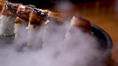 Bardaktaki kuru buz. Etkinlikte yemek servisi. Yılanbalığı suşisi buharla çevrili. Beyaz, havadar dumanlar masaya yayılıyor. Lezzetli Asya yemekleri etrafında.