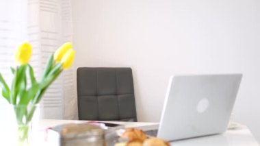 Modern mutfakta Uluslararası Kadınlar Günü kutlamalarında servis edilen yemek masası ve vazo. Kahvaltı çörekleri için dizüstü bilgisayar sarısı laleler.