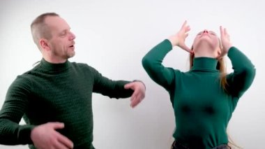 Bir adam karısını taklit eder, saçını düzeltirken yüzünü buruşturur, küçük at kuyruğunu uzatır, eğilir, arkasından tüm hareketleri tekrarlar.