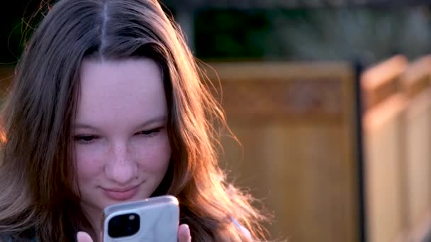 야외에서 전화로 타이핑하는 여자의 배경에 스마트폰을 산책하는 소녀를 클로즈업합니다 밖에서 — 비디오