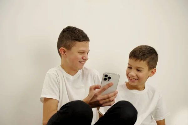 两名年轻的亚洲兄弟在智能手机上竞争白种人背景的游戏 高质量的照片 — 图库照片