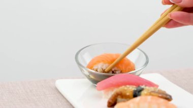 Suşi rulolarını siyah arka plana soya sosuna batır. Çok yavaş çekimde soya sosuna suşi bandırıyorum. Yüksek kalite 4k görüntü