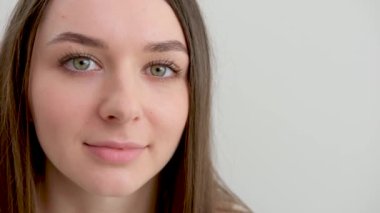 Genç bir kadının yakın plan portresi pozitif anlamda rastgele bir portredir, büyük bir gülümseme, stüdyoda beyaz arka planda poz veren güzel bir manken. Beyaz kadın portresi..