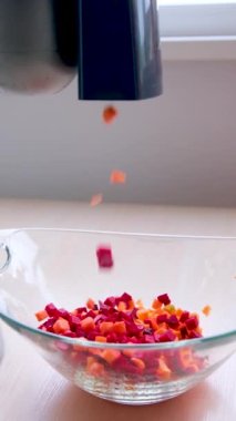 Yemek işleyicisi havuçları cam bir tabakta keser. Pancar parçalarının küp küp küp küp kesildiği bir tabakta.