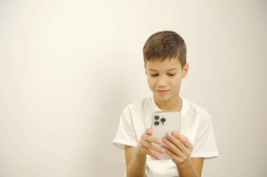Bir anaokulu öğrencisi akıllı telefon kullanarak kanepede oturur ve üzgün ve sıkıcı görünür. Yüksek kalite fotoğraf