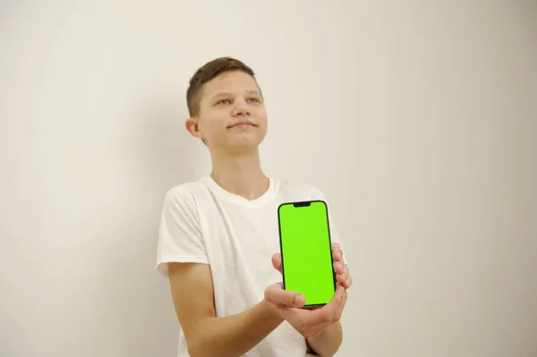 Mladý Chlapec Bílých Šatech Bílém Pozadí Drží Mobilní Telefon Zelenou — Stock fotografie