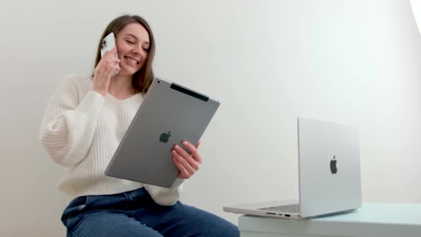 笑顔の女性学生は Skypeの先生とオンラインで勉強するために無線ヘッドフォンを身に着けています 幸せな若い女性は言語を学びます IpadのMacbookレクチャーウォッチウェビナー ノートパソコンを見てくださいカナダ2023 — ストック動画